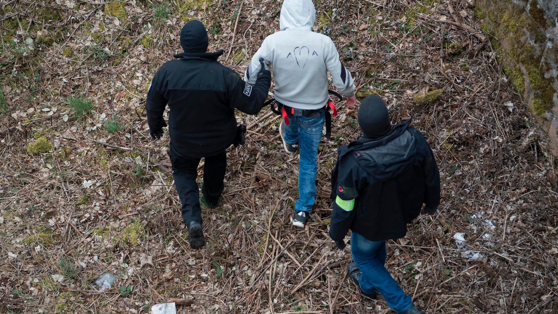 Ali B. wird von zwei maskierten Polizeibeamten begleitet: Insgesamt haben über 30 Prozessbeteiligte die Tatorte aufgesucht.