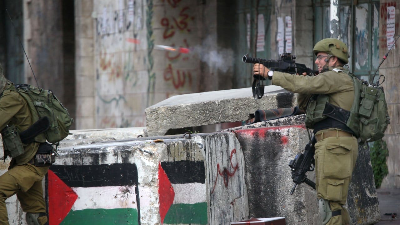 Ein israelischer Soldat feuert bei Zusammenstößen in Hebron im Westjordanland Tränengas auf palästinensische Demonstranten.