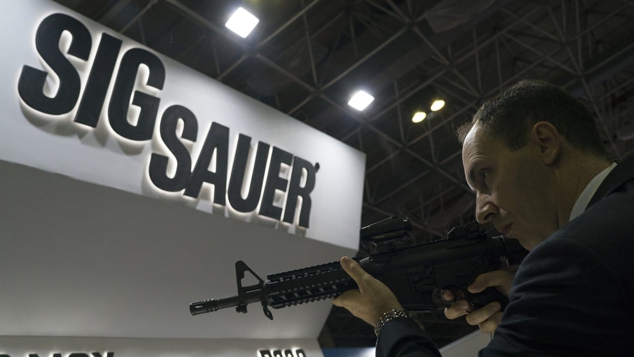 Ein Mann testet auf einer Waffenmesse ein Sig-Sauer-Gewehr.