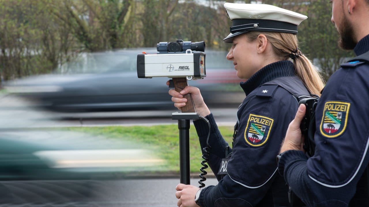 Polizisten stehen an einer Straße in Magdeburg und messen die Geschwindigkeit der vorbeifahrenden Verkehrsteilnehmer.