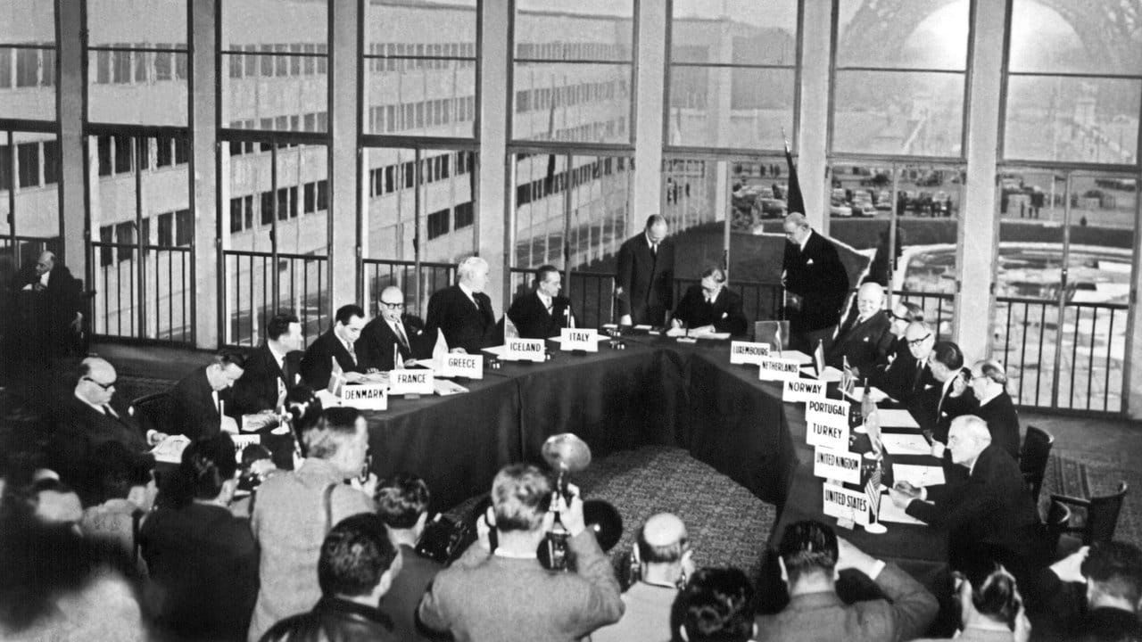 Fotografen dokumentieren den historischen Moment, in dem der britische Außenminister Anthony Eden im Oktober 1954 die Vereinbarung zum Beitritt der Bundesrepublik Deutschland in die Nato unterzeichnet.