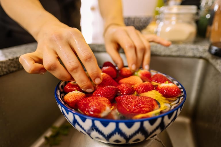 Waschen Sie Erdbeeren immer erst kurz vor dem Verzehr samt Blättern und Stielen. Am besten geben Sie sie in eine Schale mit Wasser und waschen sie so kurz ab.