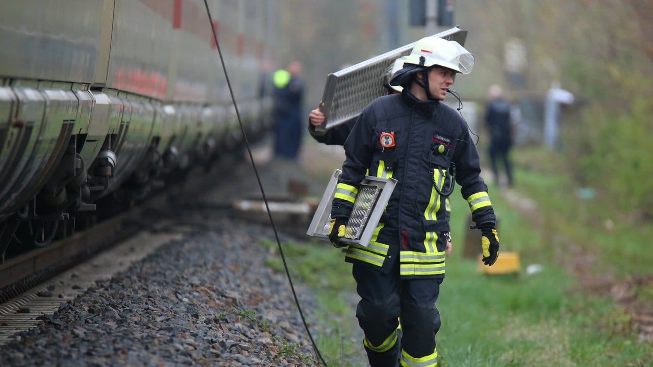 Umsteigen bitte: Feuerwehrleute tragen Brückenteile, um den ICE mit dem Ersatzzug zu verbinden.