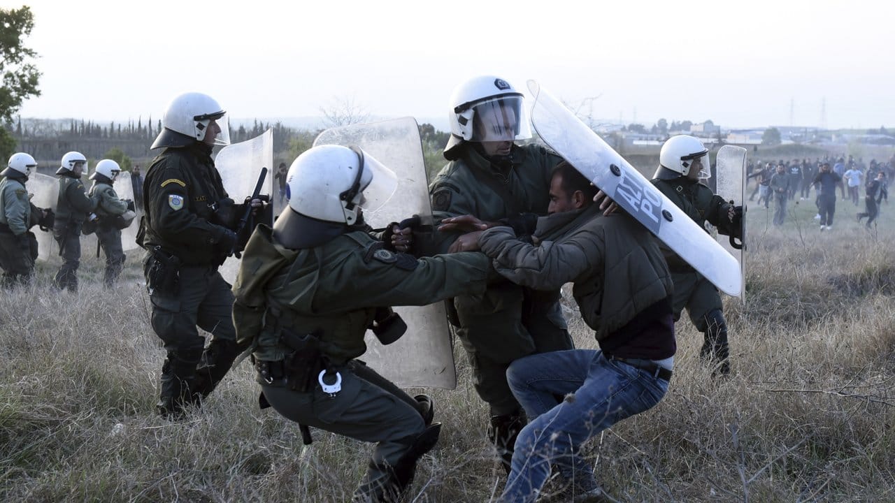 Ein Mann wird von drei Bereitschaftspolizisten bei Auseinandersetzungen während eines Protests vor einem Flüchtlingslager festgenommen.