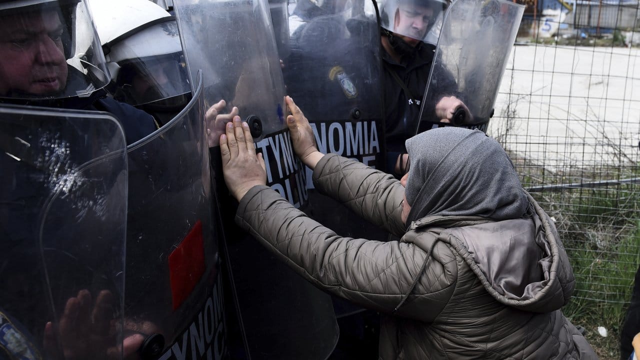 Eine Frau und Polizisten der Bereitschaftspolizei stoßen vor einem Flüchtlingslager westlich von Thessaloniki aufeinander.