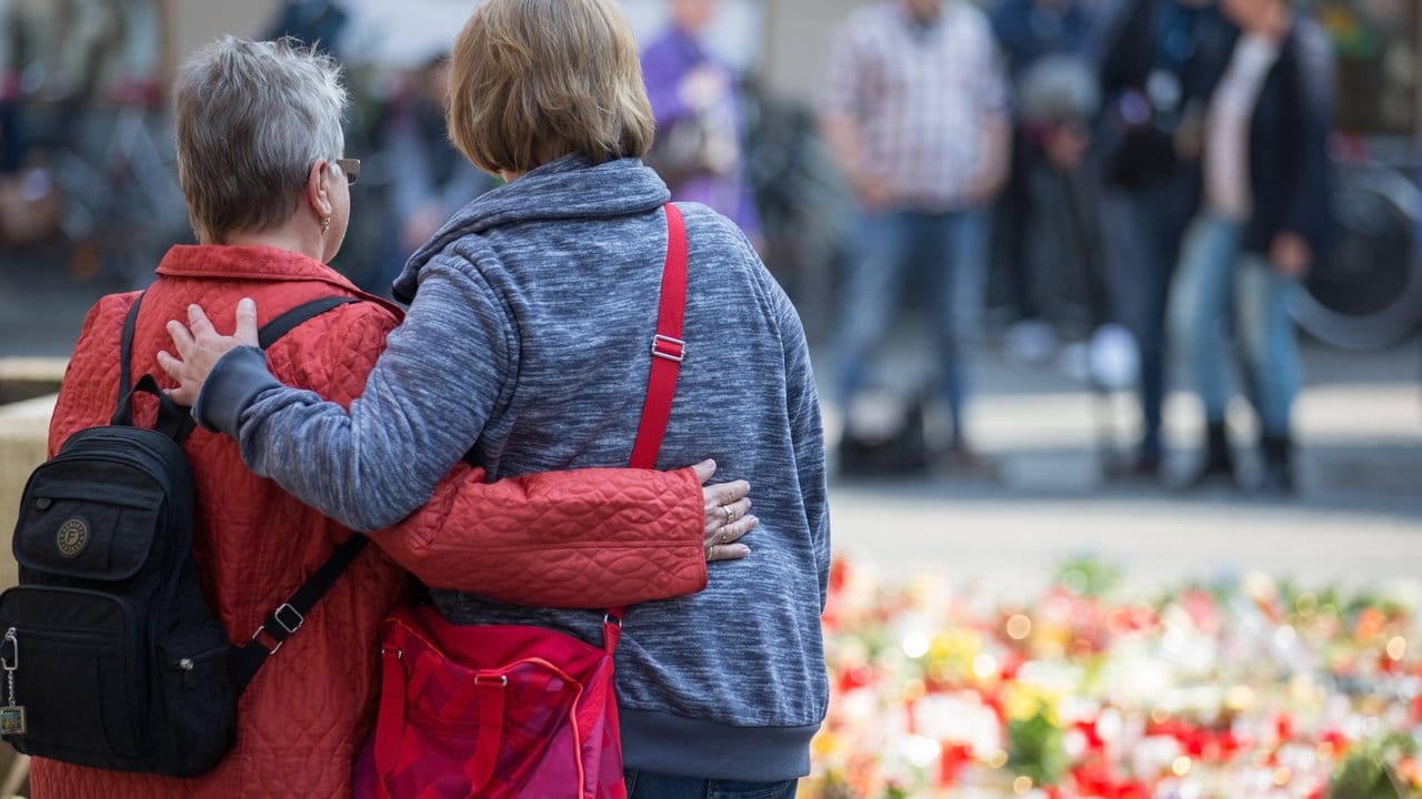 Zwei Trauernde Personen stehen vor einem Meer von Trauerkerzen und Blumen am Tatort, der Münsteraner Gaststätte "Großer Kiepenkerl".