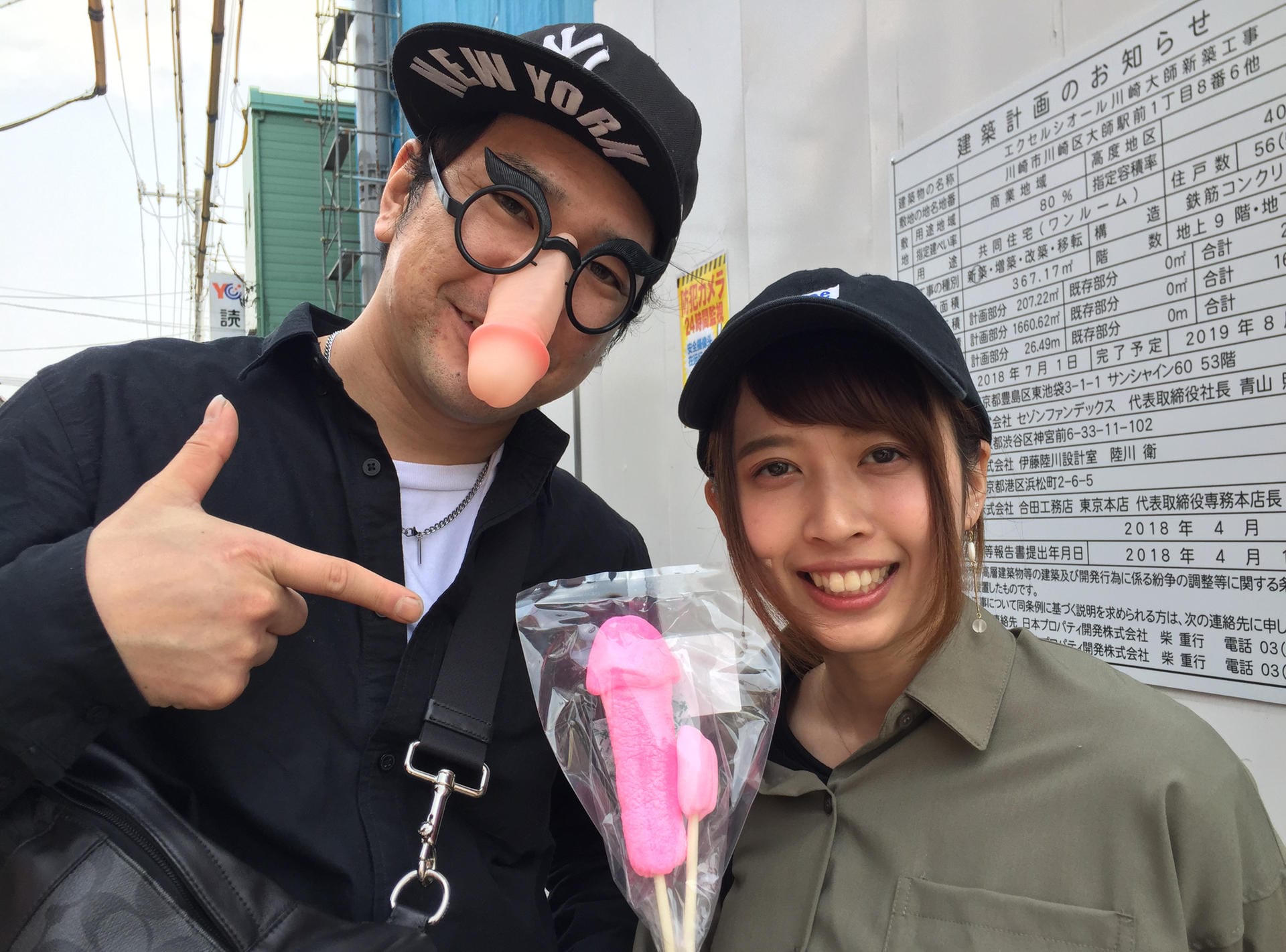 Besucher des Phallus-Festivals zeigen Souvenirs: Die japanischen YouTuber Shinya (l) und Yuriyuri zeigen beim Phallus-Festival einen rosafarbenen Penis-Lolli.