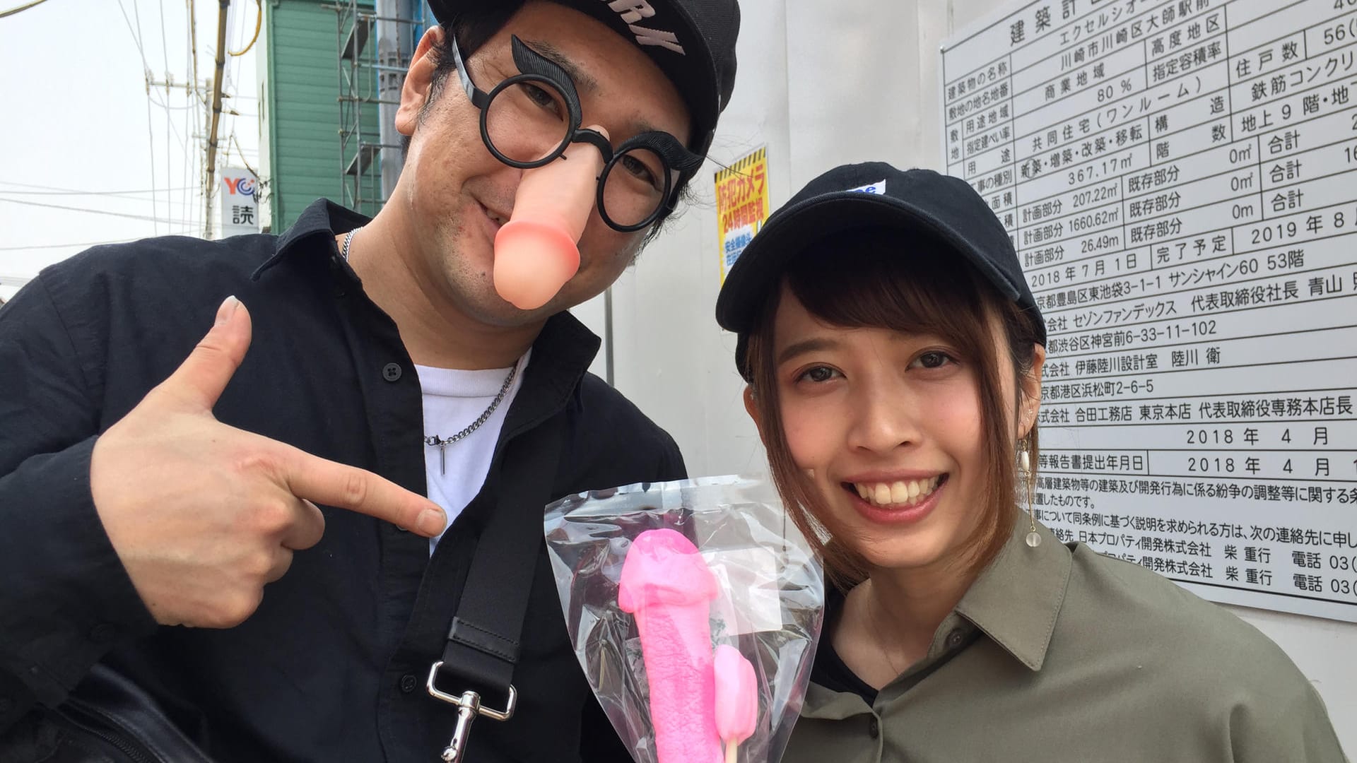 Besucher des Phallus-Festivals zeigen Souvenirs: Die japanischen YouTuber Shinya (l) und Yuriyuri zeigen beim Phallus-Festival einen rosafarbenen Penis-Lolli.