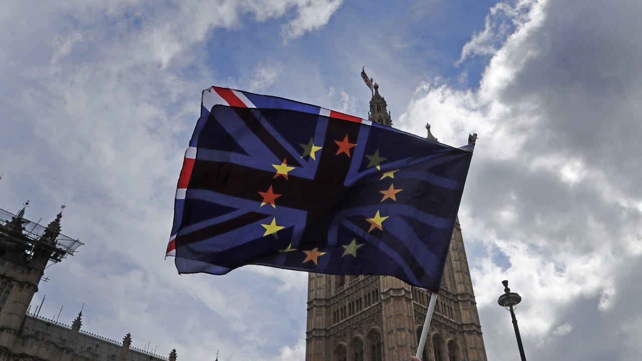 Ein Demonstrant schwenkt vor den Parlamentsgebäuden in Westminster eine britische und eine EU-Fahne.