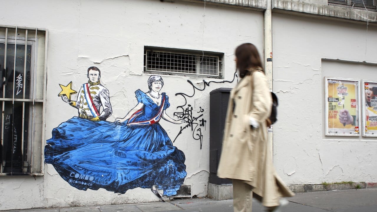 Eine Passantin schaut sich in Paris ein Wandbild des französischen Straßenkünstlers Combo an, das Emmanuel Macron und Theresa May zeigt.