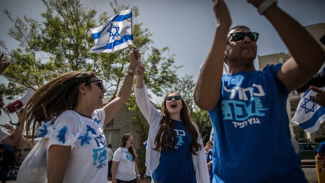 Unterstützer des Bündnisses Blau-Weiß von Benny Gantz singen und tanzen vor einem Wahllokal in Tel Aviv.
