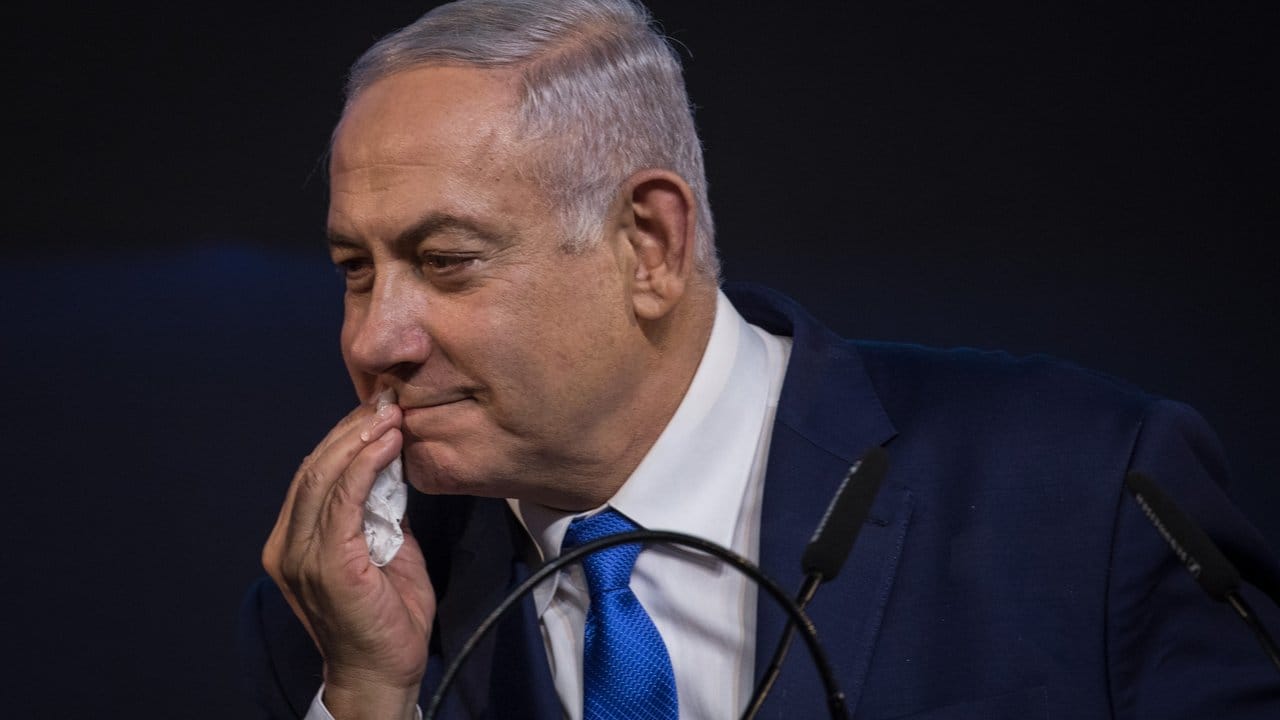 Benjamin Netanjahu entfernt Spuren von Lippenstift nach einem Gratulationskuss seiner Frau.