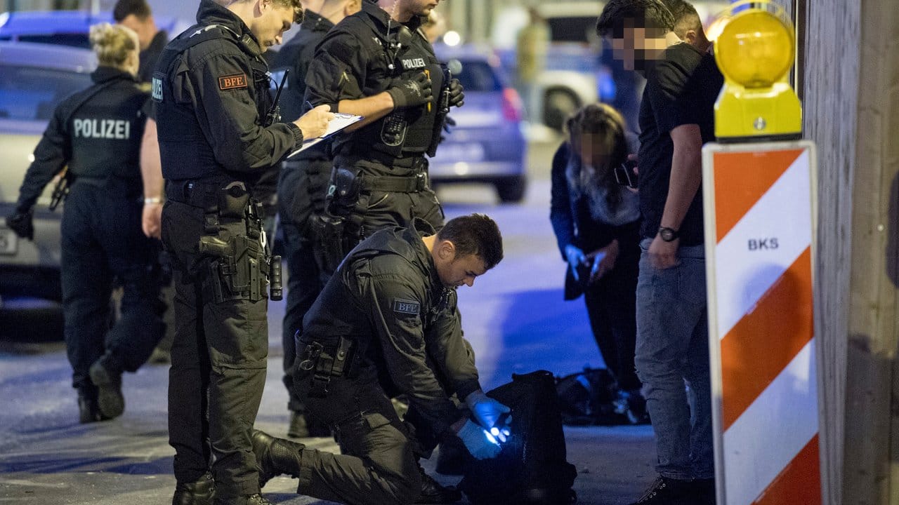 Im Bahnhofsviertel von Frankfurt am Main durchsucht ein Polizist den Rucksack eines Mannes nach Drogen.