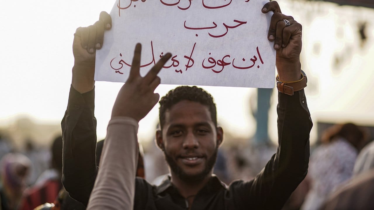 Ein Demonstrant hält ein Plakat, auf dem auf Arabisch steht: "Ibn Ouf ist ein Kriegsverbrecher, Ibn Ouf vertritt mich nicht".