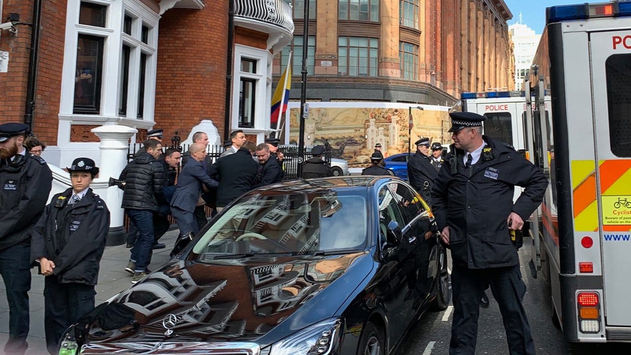 Die Polizei bringt Julian Assange (verdeckt) aus der ecuadorianischen Botschaft heraus.