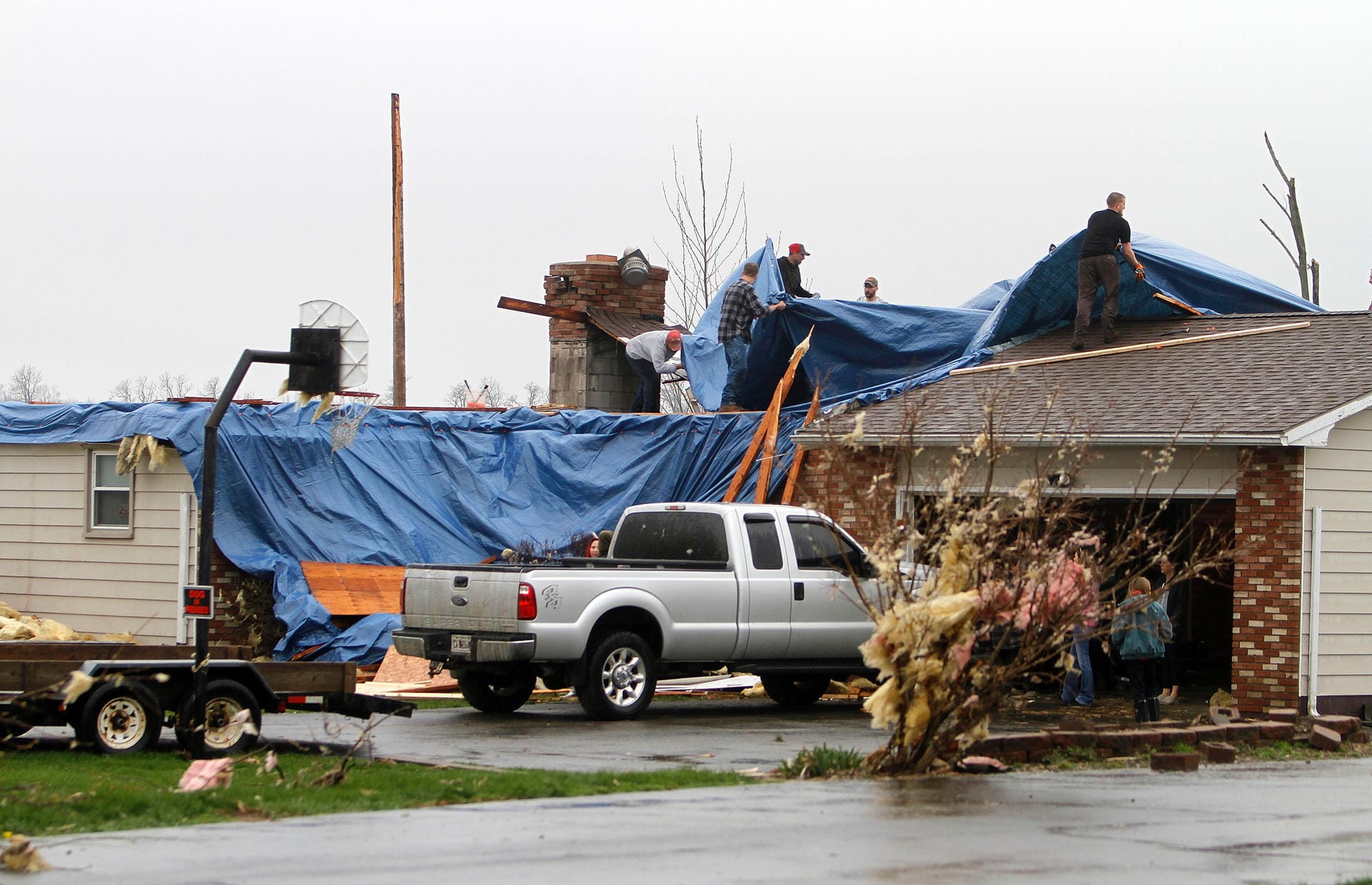 Männer decken mit einer Plane ein beschädigtes Dach ab: Nach Verwüstungen und Toten im Süden der USA ist eine Unwetterfront mit Sturmböen und schweren Regenfällen in den Nordosten des Landes vorgerückt.