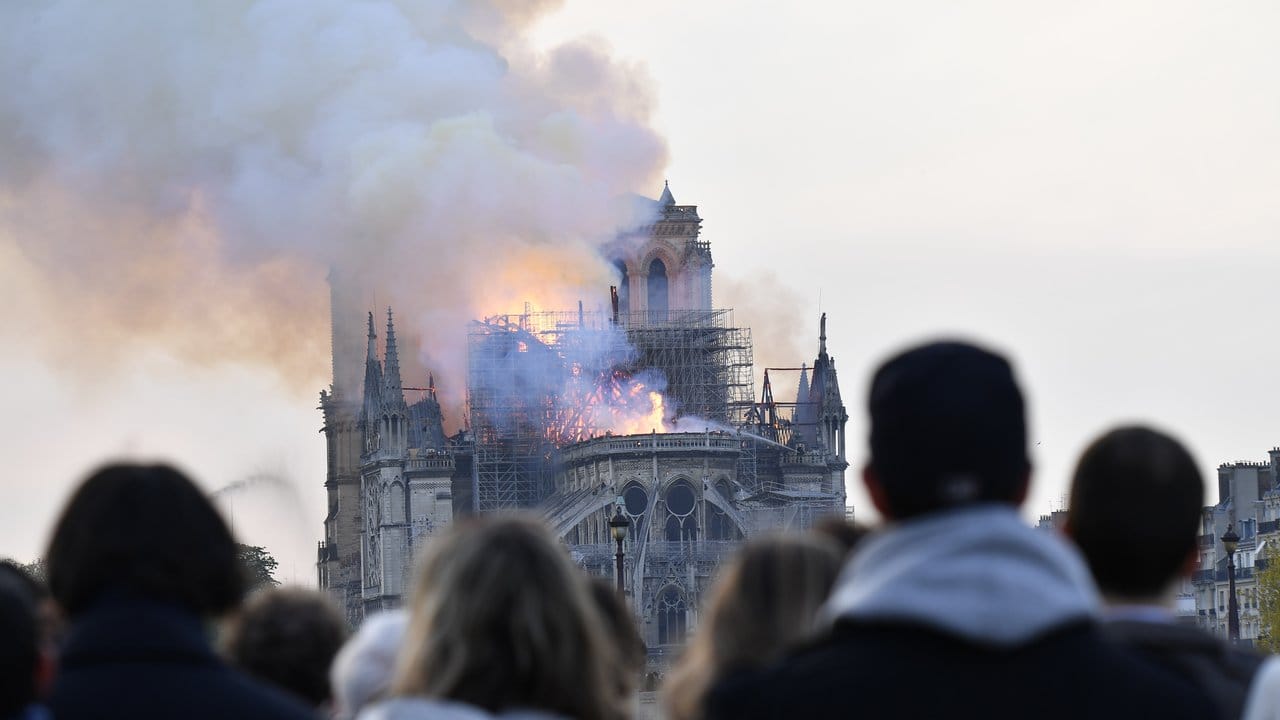 Menschen schauen zum Rauch, der von der Kathedrale Notre-Dame aufsteigt.