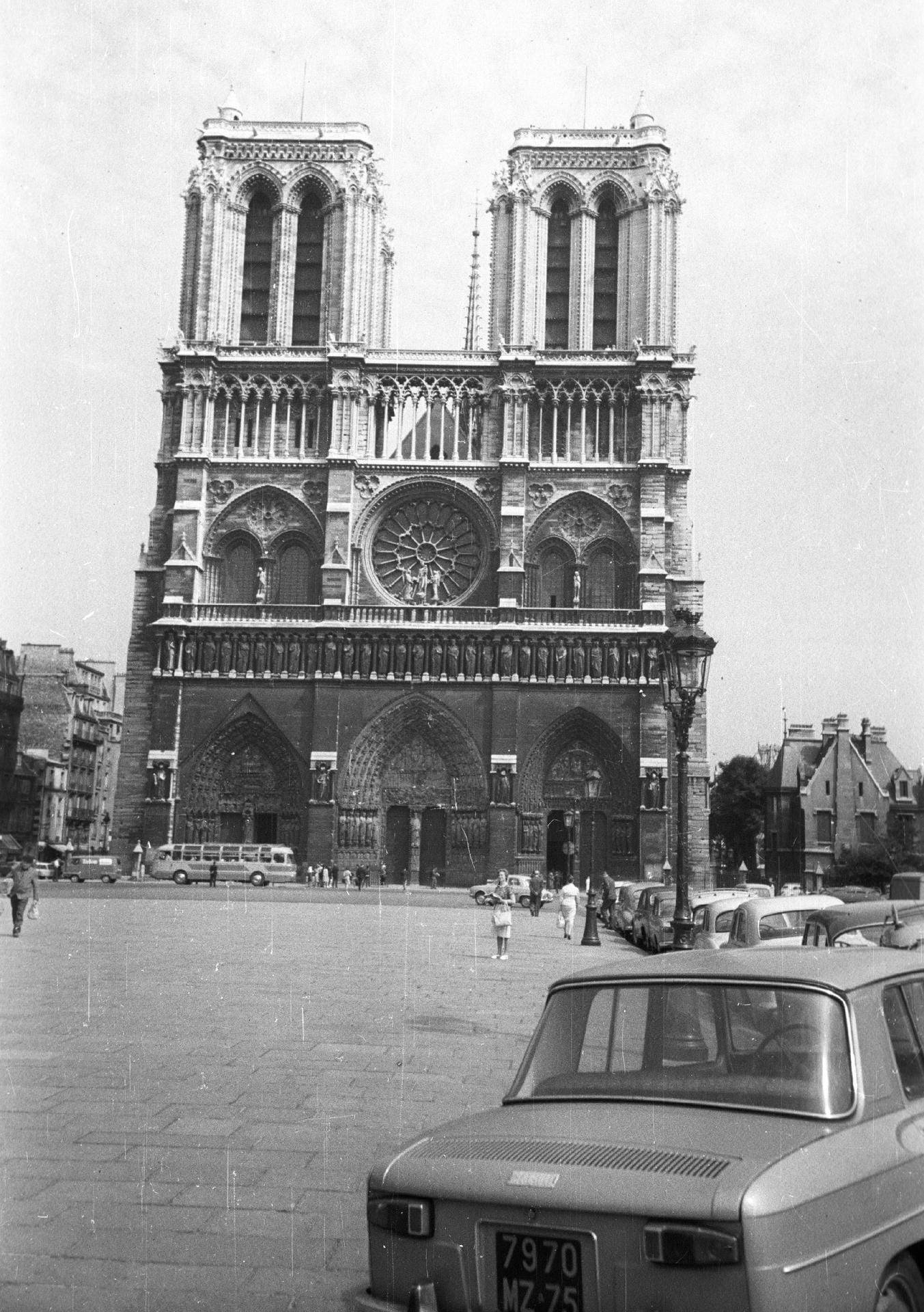 Westfassade der Kathedrale, 1964: Im Jahr 1250 vollendet, ist die Westfassade der Kirche eins der größten Erkennungsmerkmale von Notre-Dame. Sowohl an dieser Fassade, als auch an den Querhäusern verfügt die Kathedrale über bedeutende Figurenportale. Auch die mittig angeordnete Rosette von farbigen Fenstern der Westfassade von Notre-Dame ist weltweit bekannt.