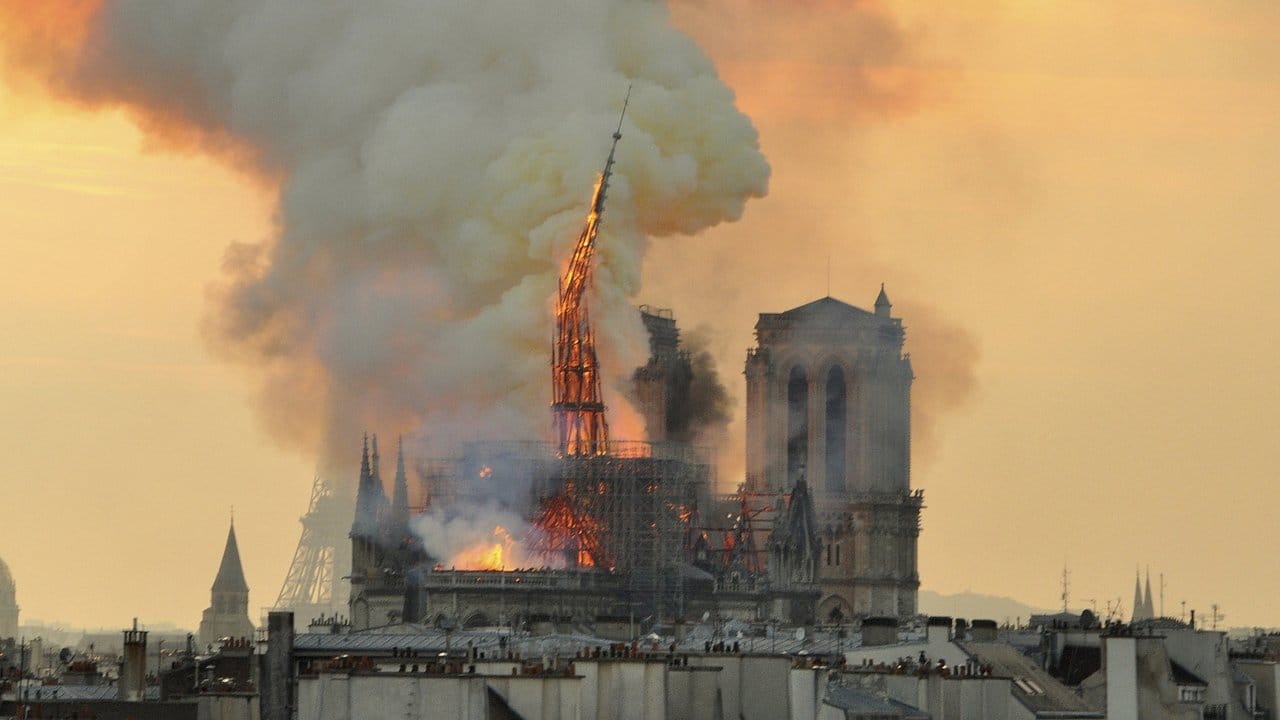 Flammen und Rauch schlagen aus der Kathedrale Notre Dame auf, der kleine Spitzturm (M) beginnt einzustürzen.