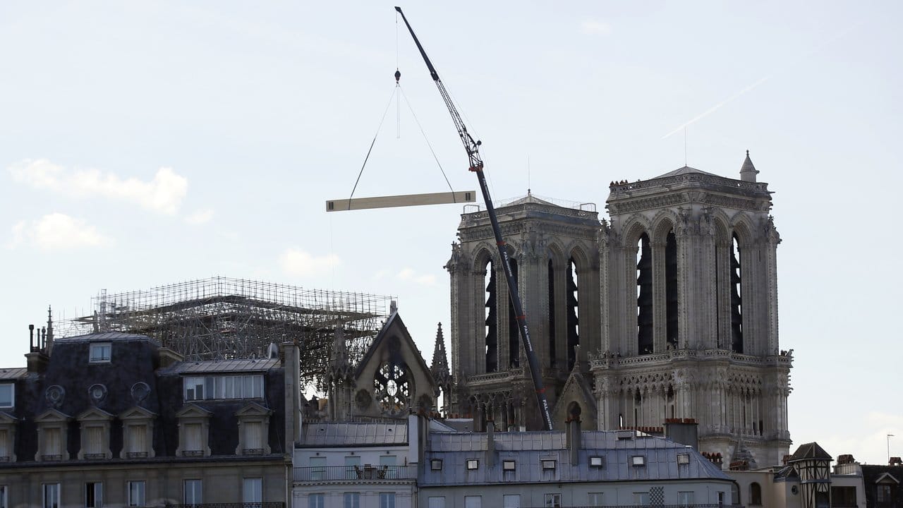 Ein Kran senkt eine hölzerne Tragkonstruktion auf die Kathedrale Notre-Dame ab.