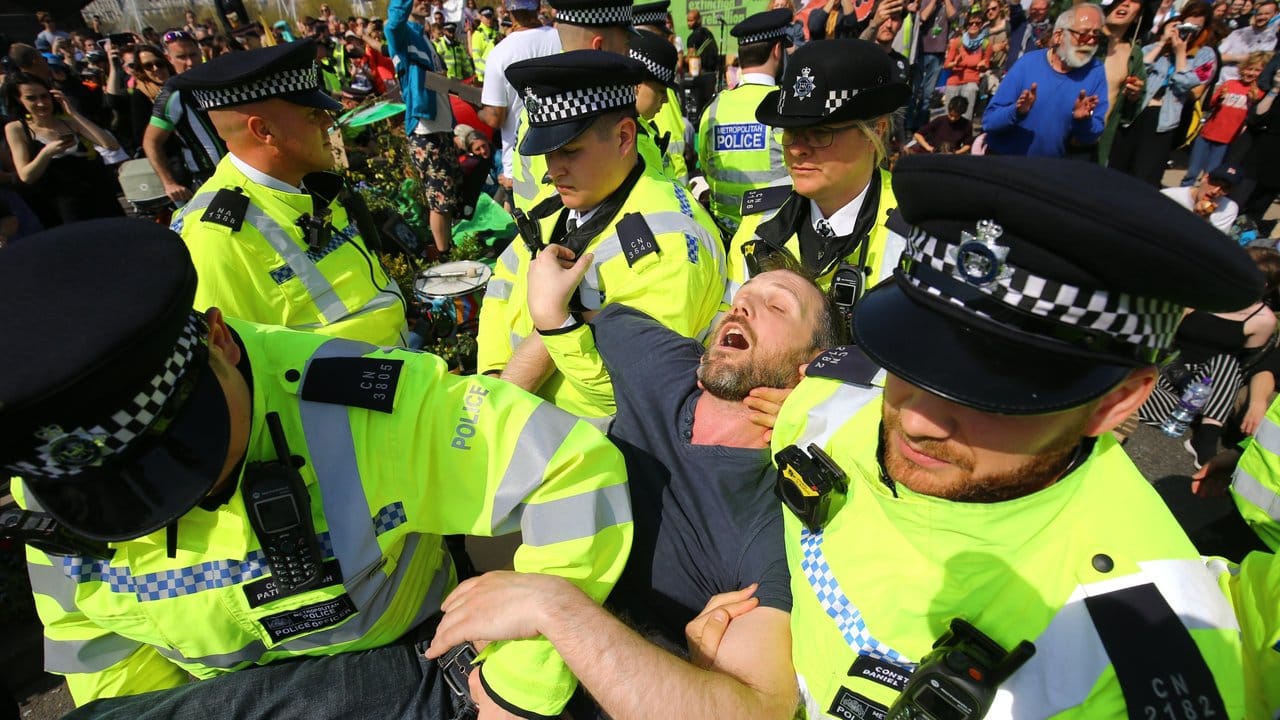 Polizisten tragen einen Demonstranten während einer Protestaktion auf der Waterloo Bridge in London weg.