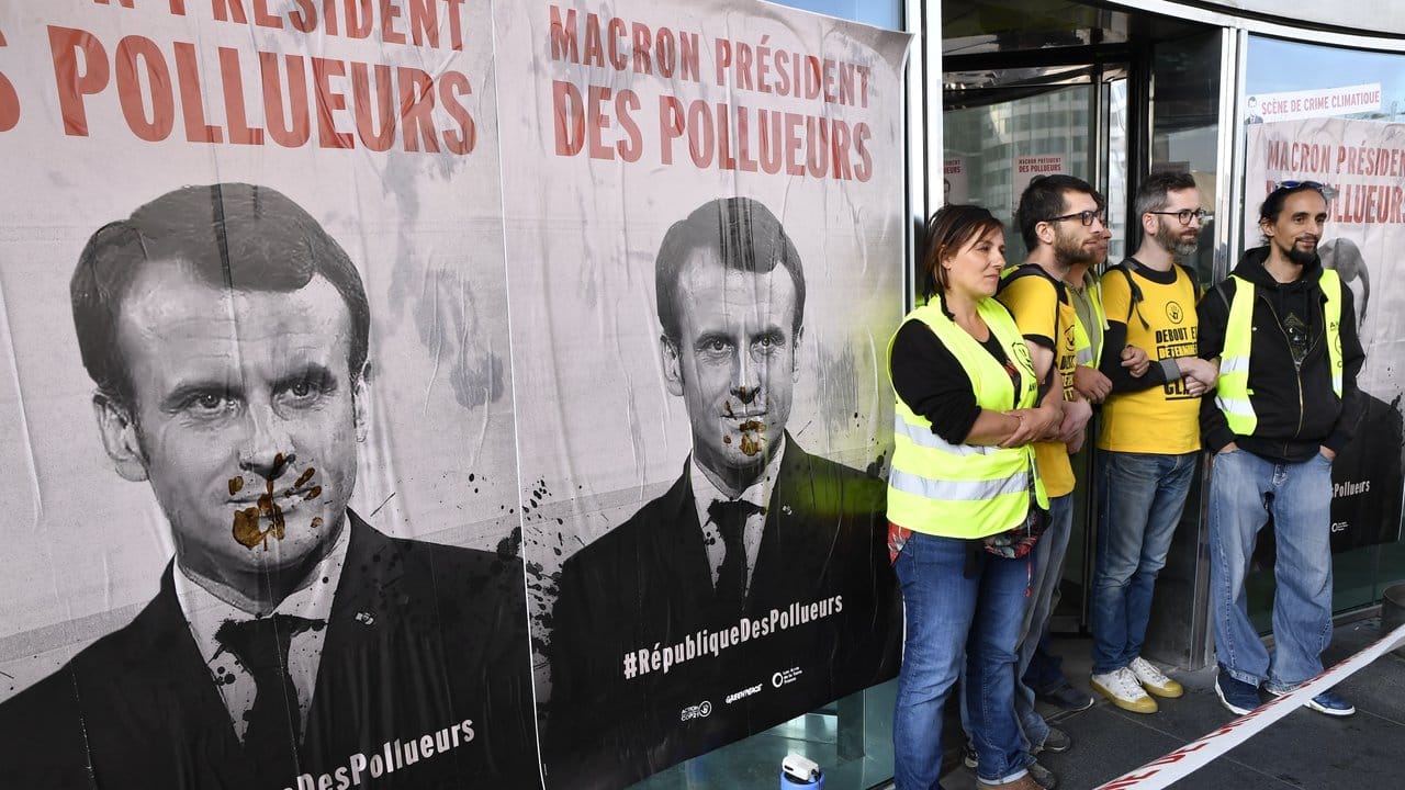 "Macron Präsident der Umweltverschmutzer" steht auf Plakaten, die Demonstranten in Paris aufgehängt haben.