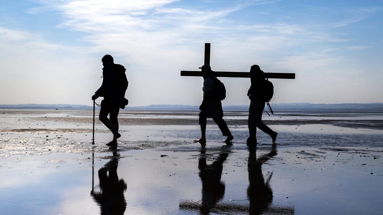 Pilger tragen während der Osterwallfahrt ein Kreuz zur Heiligen Insel Lindisfarne an der Nordostküste Northumberlands.