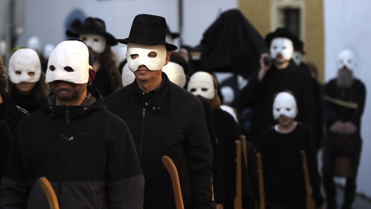 Teilnehmer einer Osterprozession gehen in schwarzen Gewändern und weißen Masken durch die Straßen von Budweis in Tschechien.