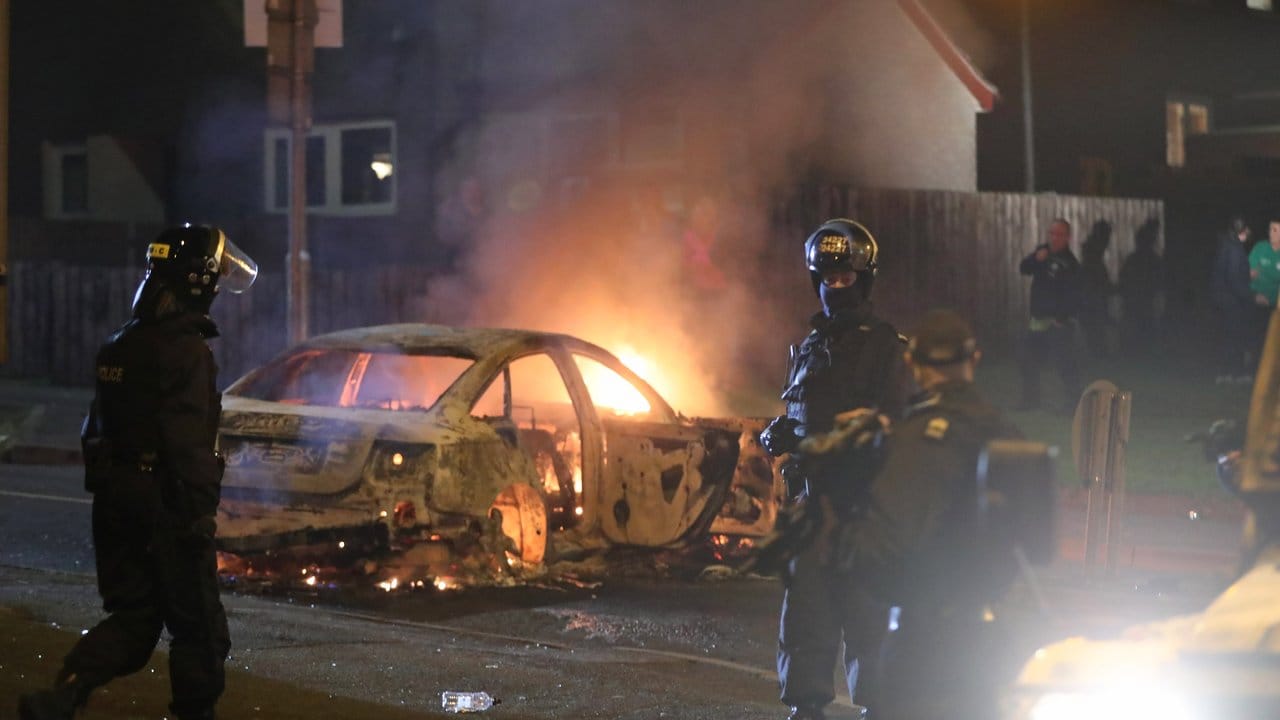 Polizisten vor einem brennenden Auto in Creggan.
