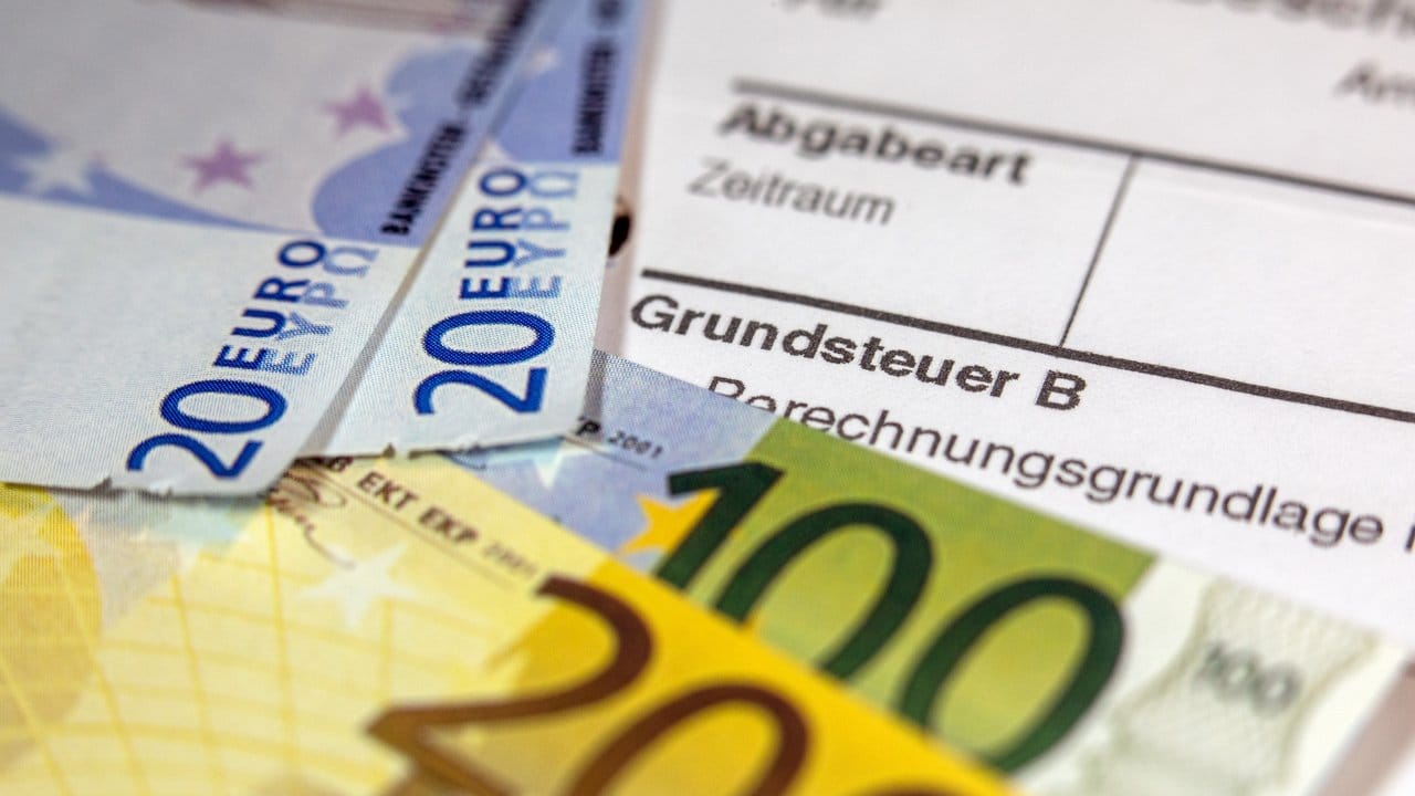 Euro-Geldscheinen liegen auf einem Abgabenbescheid für die Entrichtung der Grundsteuer.