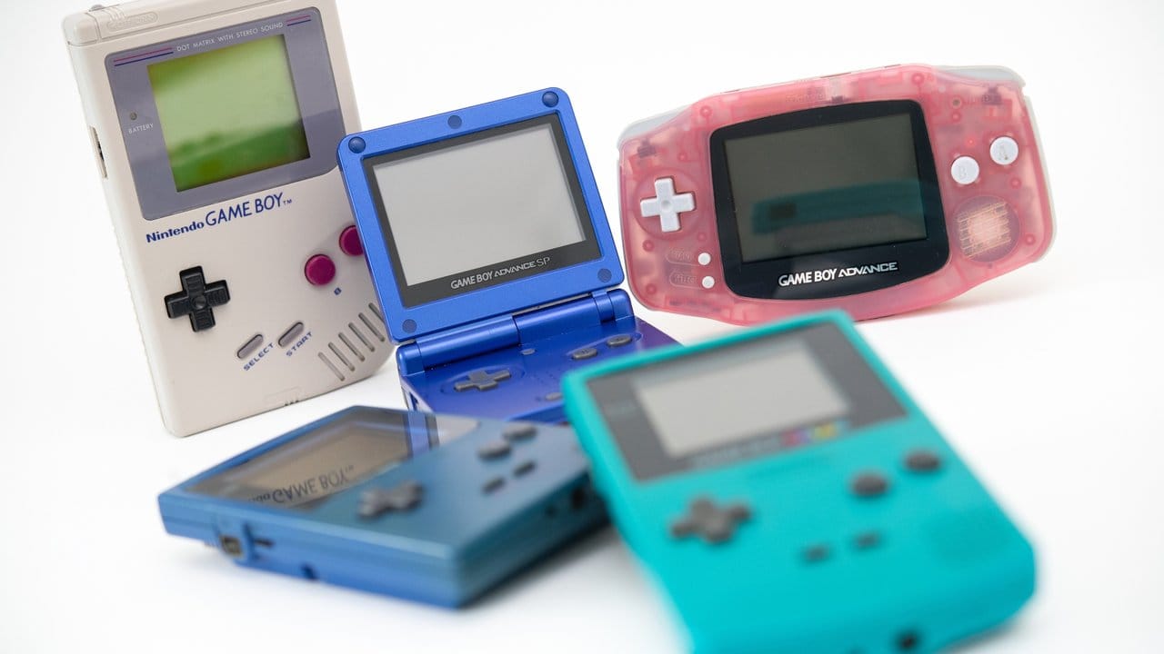 Der erste Game Boy (l in Grau) erhielt über die Jahre etliche Nachfolger wie den Game Boy Pocket (blau, liegend), den Game Boy Advance SP (Mitte, aufgeklappt), den Game Boy Advance (r, rosa) und den Game Boy Color (vorne, mit Farbdisplay).