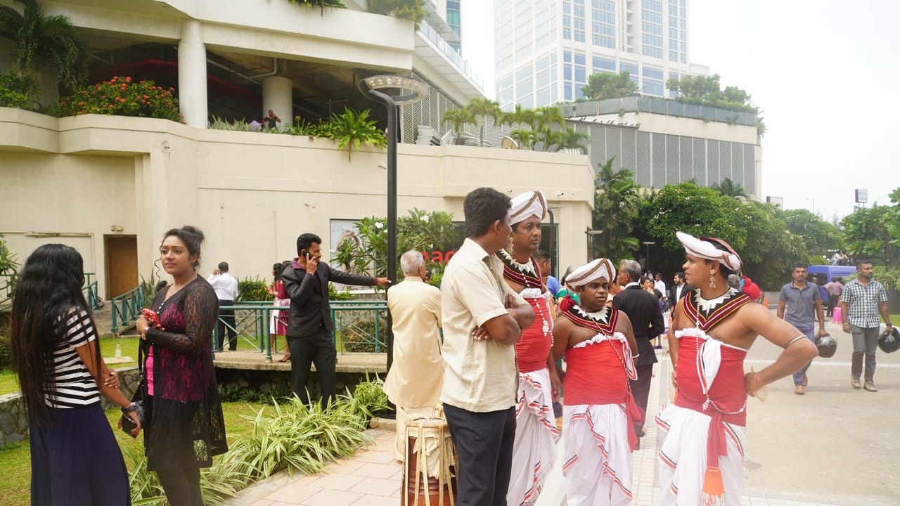 Tänzer in traditionellen Kostümen warten nach einer Explosion vor einem Hotel in Colombo.