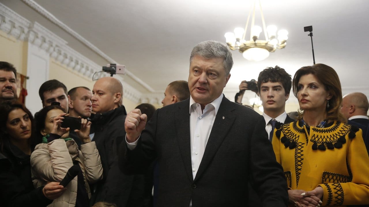 Amtsinhaber Petro Poroschenko (M) spricht in einem Wahllokal, seine Frau Maryna (r) steht neben ihm.