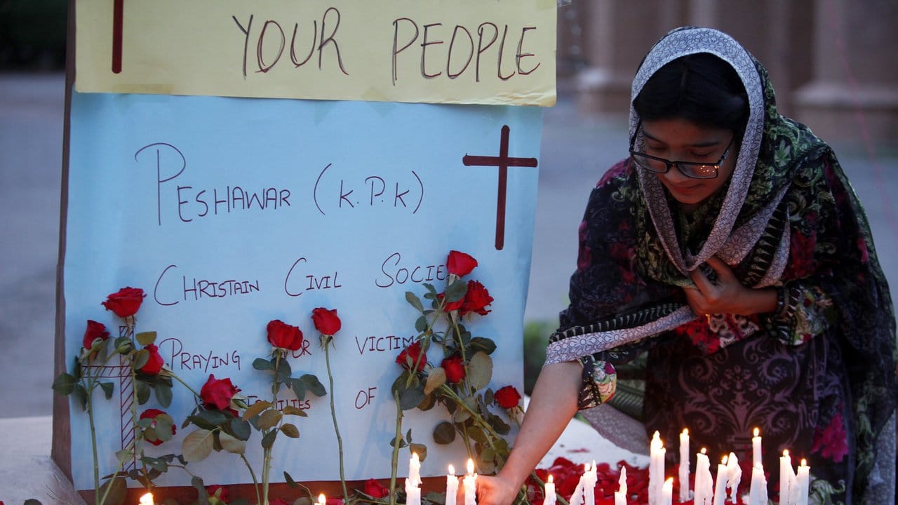 Eine Christin zündet eine Kerze bei einer Mahnwache in Pakistan für die Opfer an.