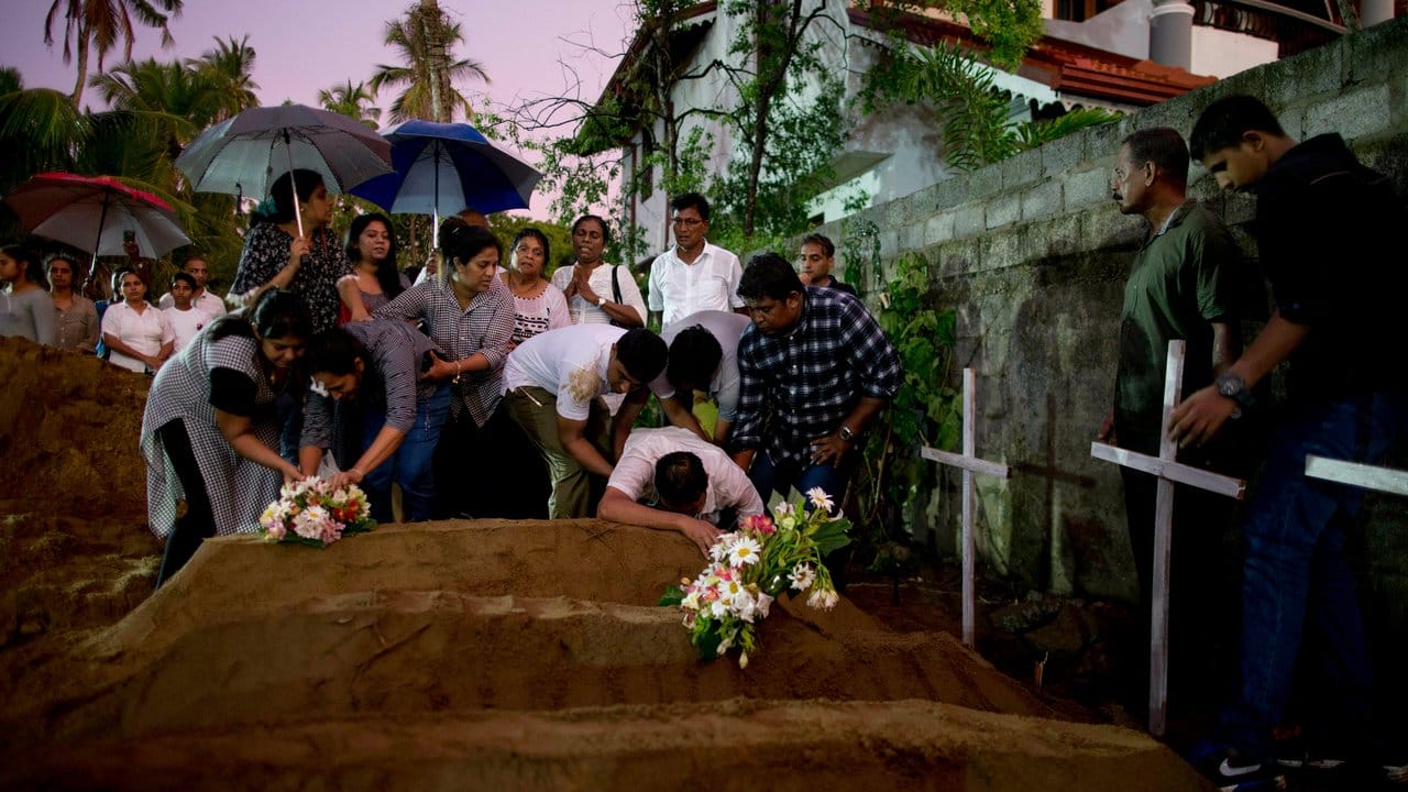 Verwandte platzieren Blumen nach der Beerdigung von Opfern, die bei den Bombenexplosionen am Ostersonntag starben.