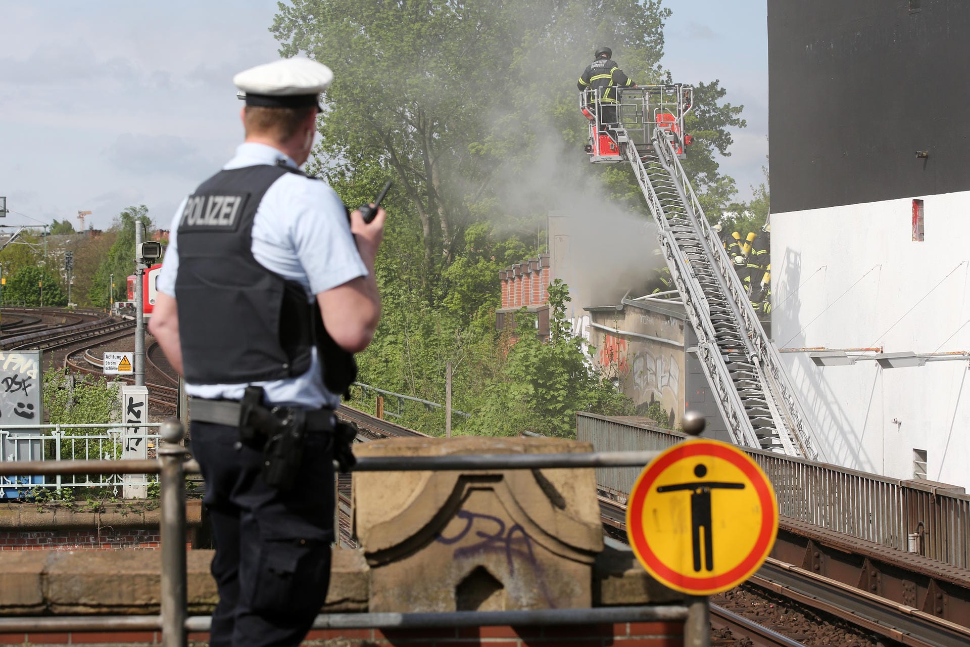 Feuer im Schanzenviertel: Ein Polizist sichert von einem nahen Bahnhof aus den Einsatz der Feuerwehr.