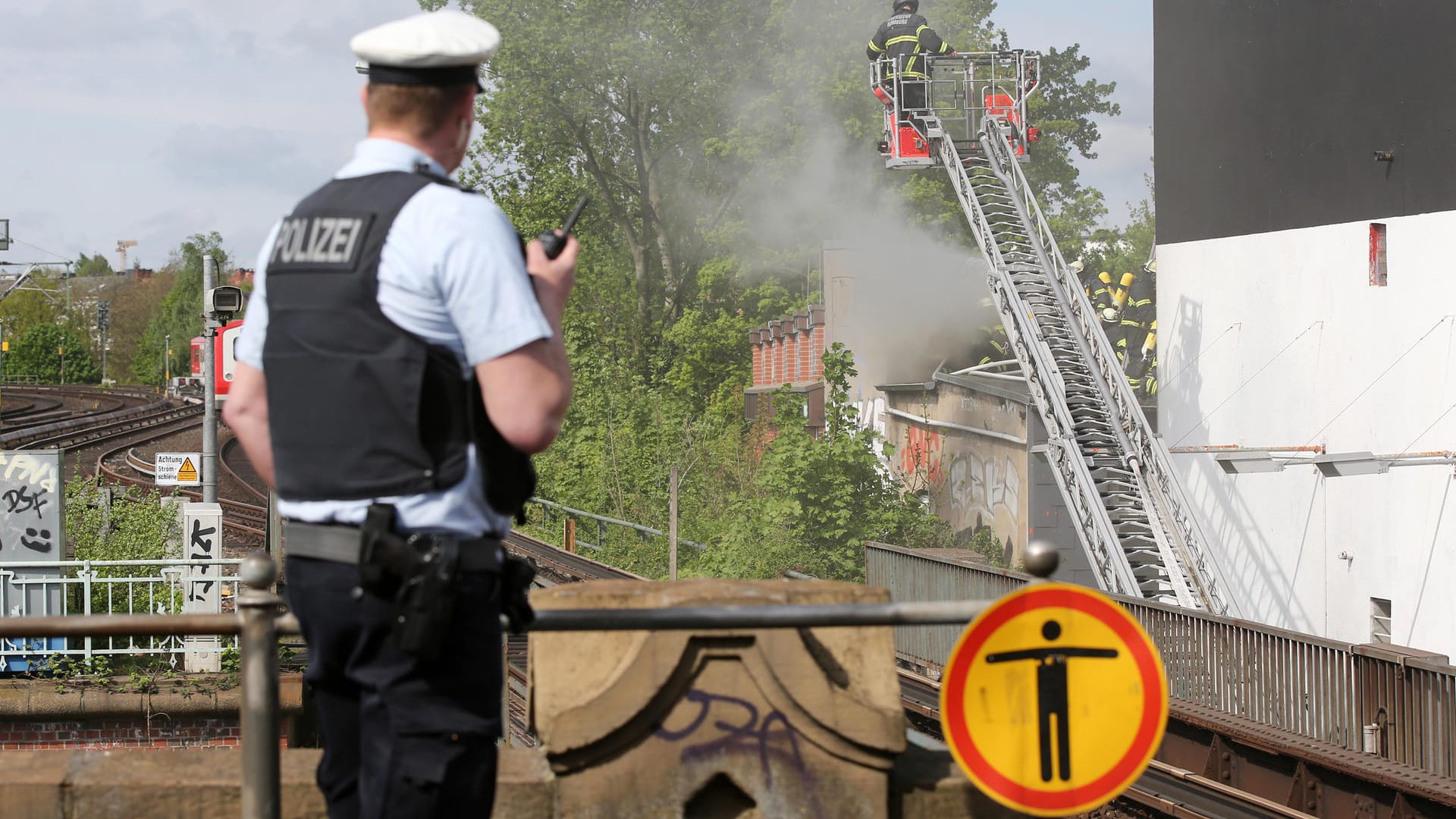 Feuer im Schanzenviertel: Ein Polizist sichert von einem nahen Bahnhof aus den Einsatz der Feuerwehr.