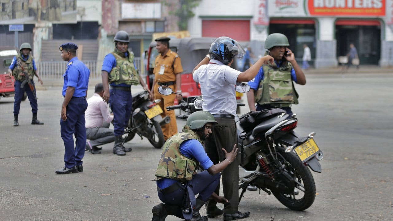Soldaten führen an einer Straße in Colombo Personenkontrollen durch.