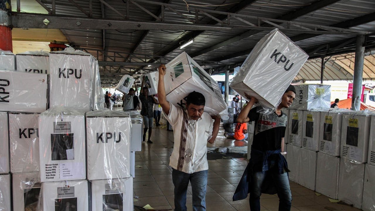 Wahlhelfer tragen Pakete mit Stimmzetteln, die an Wahlstationen verteilt werden.