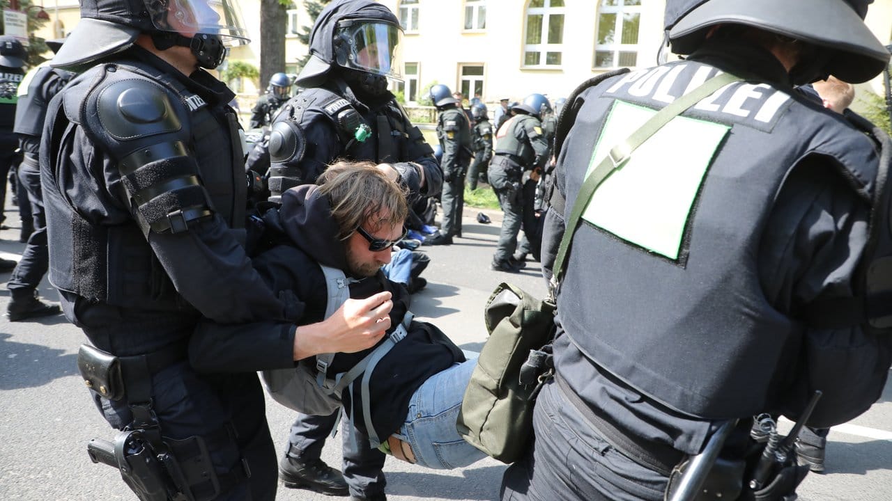 Polizisten lösen in Erfurt eine Sitzblockade auf einer Straße in Erfurt auf und tragen Demonstranten weg, die eine Kundgebung der AfD verhindern wollten.