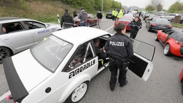 Getunter Sportwagen mit der Aufschrift "Eurorally": Eine Beamtin der Polzei steht vor einer scheinbar endlosen Schlange von Autos.