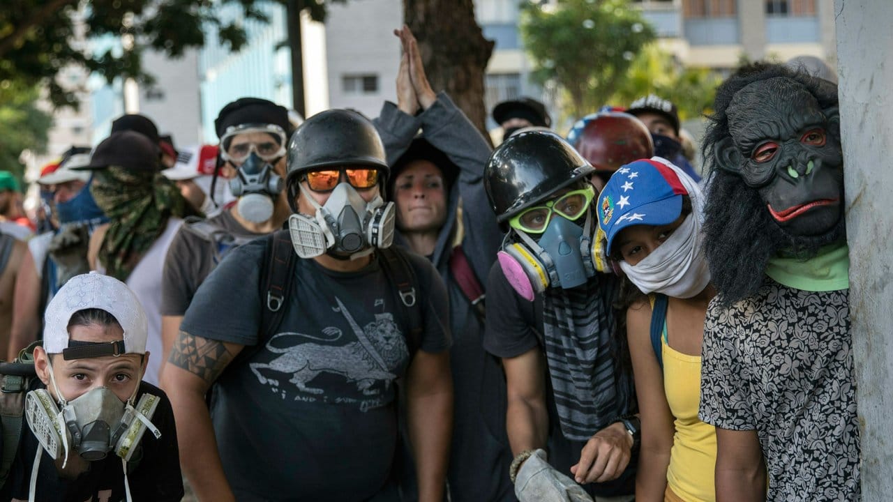 Regierungsgegner beobachten Sicherheitskräfte während Zusammenstößen in Caracas.