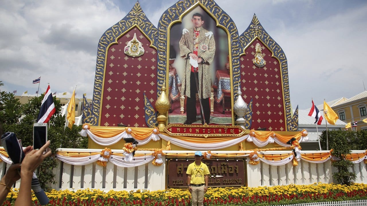 Ein Mann lässt sich mit einem Smartphone vor einem überlebensgroßen Foto des neuen Königs von Thailand fotografieren. Ein Mann lässt sich mit einem Smartphone vor einem überlebensgroßen Foto des neuen Königs von Thailand fotografieren.