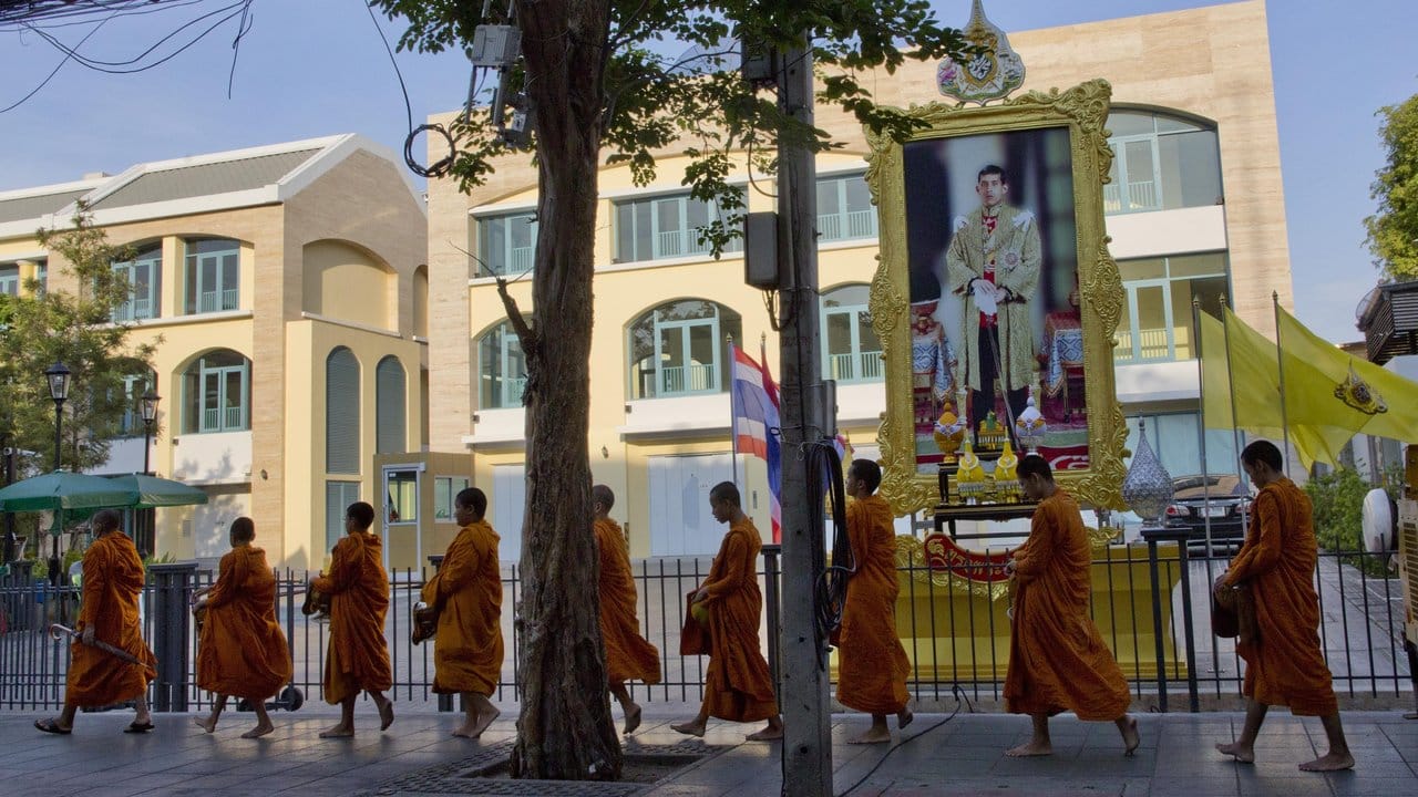 Buddhistische Mönche ziehen an einem Porträt von Thailands neuen König vorbei.