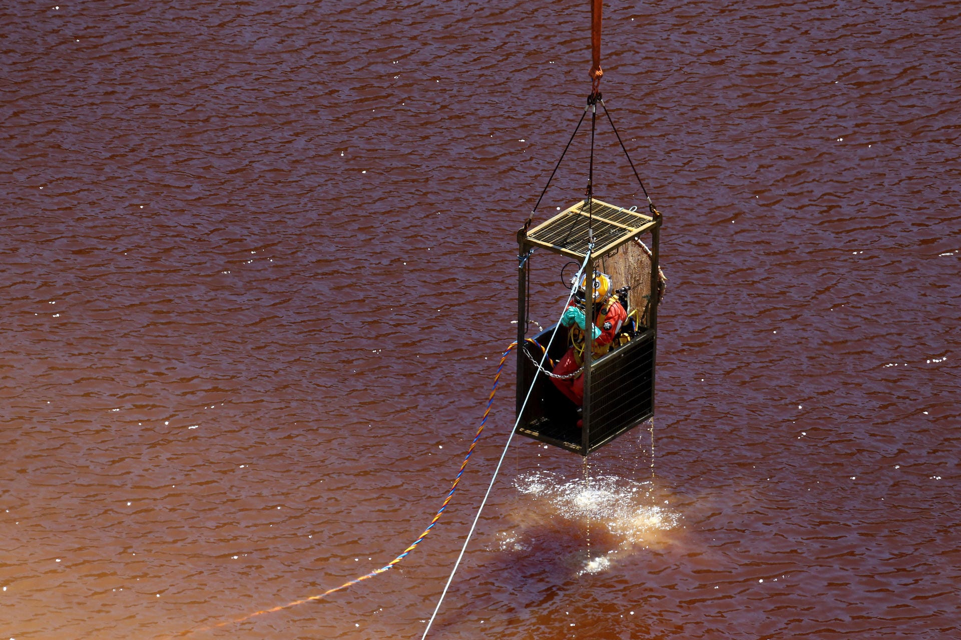 Ein Taucher in einem Käfig wird aus dem See gehoben, nachdem er dort nach weiteren Koffern, in denen Leichenteile vermutet werden, suchte. Der See ist durch Chemikalien verseucht, Taucher können nur mit Schutzkleidung darin schwimmen.
