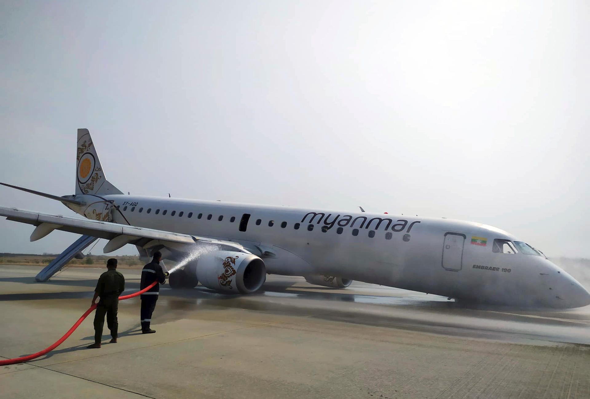 Feuerwehrleute löschen nach einer Notlandung das Flugzeug der Myanmar National Airline (MNA) auf dem International Airport: Bei der Notlandung kam es zu einem starken Funkenschlag.