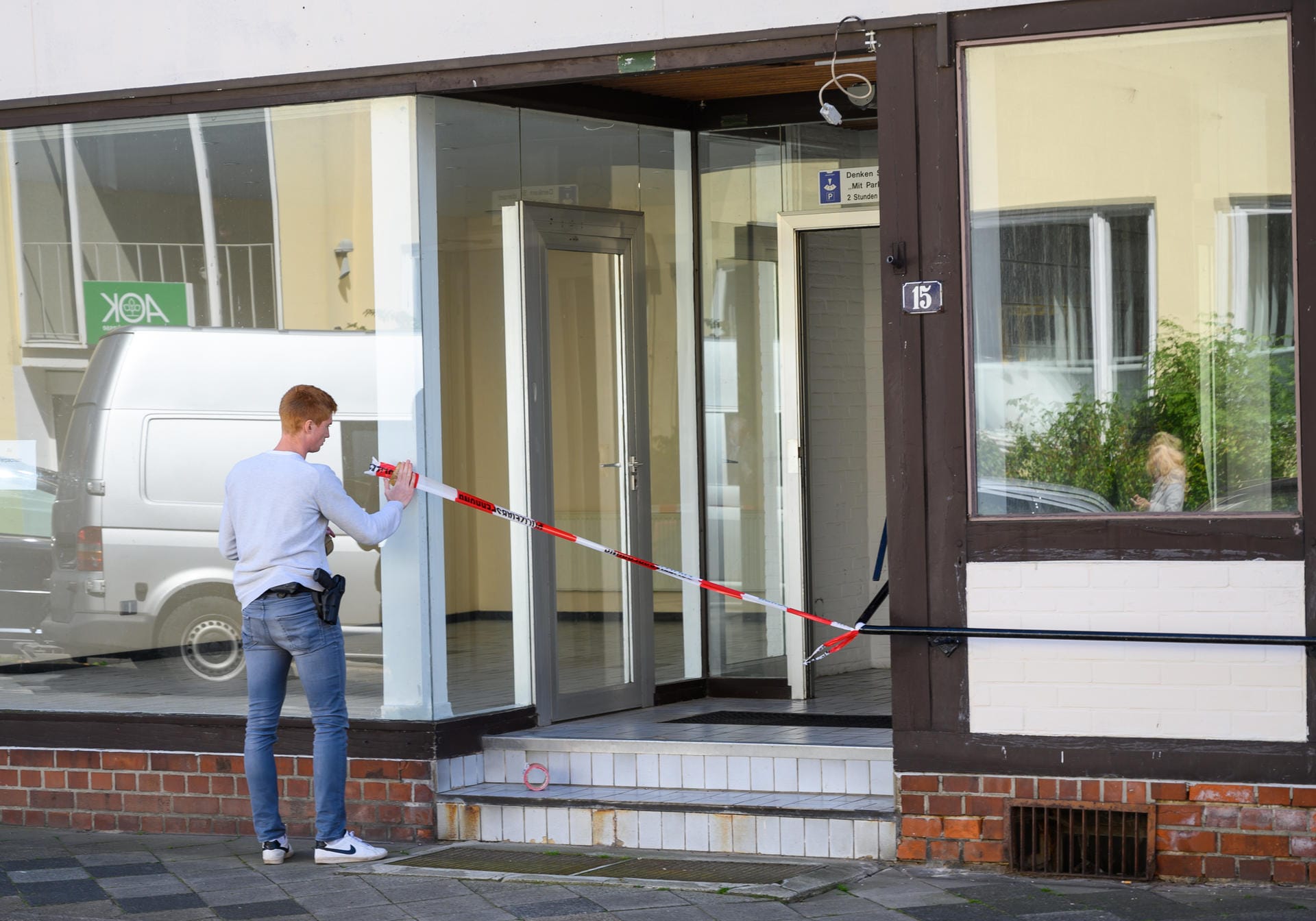 Ein Polizist sichert den Eingang eines Hauses mit Absperrband: Die toten Frauen sind in der Wohnung eines der Passauer Opfer entdeckt worden.