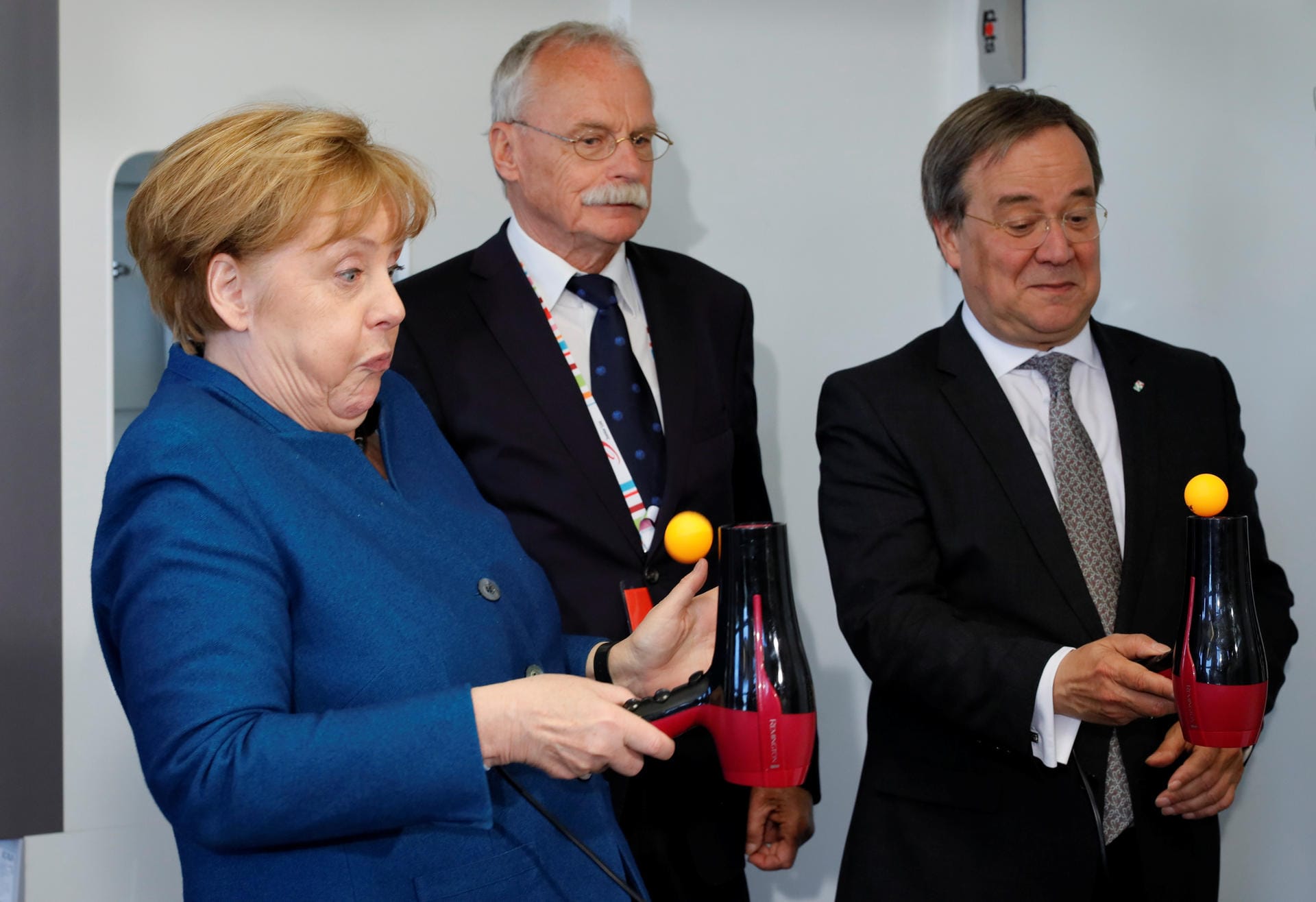 Bundeskanzlerin Angela Merkel bei einem Experiment mit Tischtennisball und Fön, gemeinsam mit Ernst-Andreas Ziegler und Armin Laschet (r.), dem Ministerpräsidenten von Nordrhein-Westfalen.