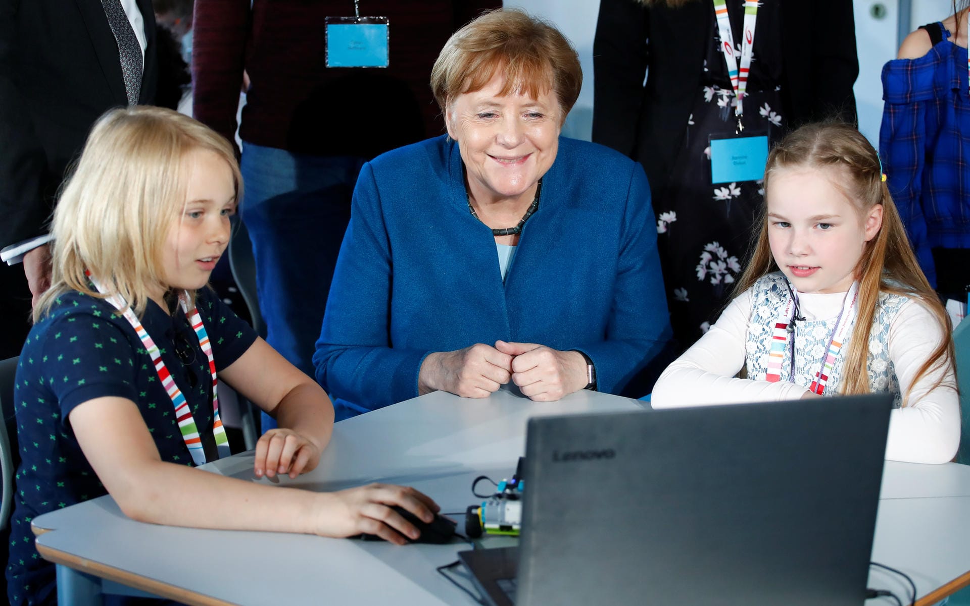 Bundeskanzlerin Angela Merkel nimmt an einem Experiment der achtjährigen Junior-Studentinnen Keke (l.) und Sophia (r.) teil.