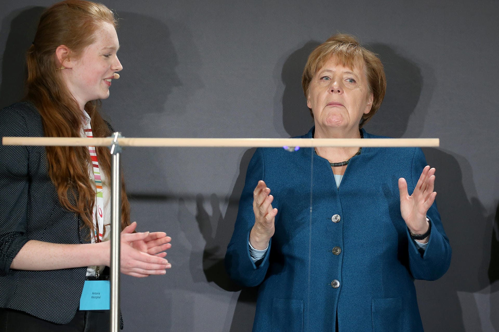 Bundeskanzlerin Angela Merkel verfolgt an der Junior Universität neben der Schülerin Antonia Westphal ein Pendel Experiment.